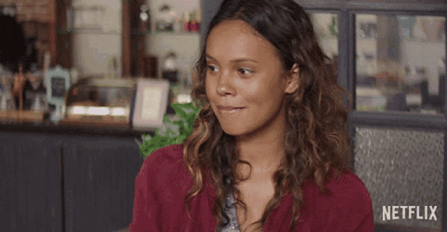 a woman with curly hair is smiling in front of a netflix logo