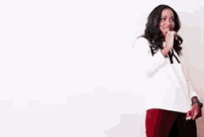 a woman is standing in front of a white wall wearing a white sweater with the word fake on it .