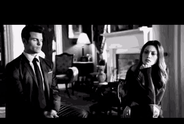 a man in a suit and tie sits next to a woman in a black and white photo