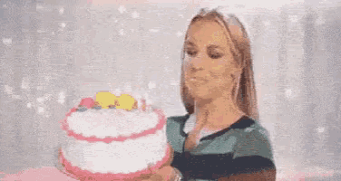 a woman is blowing out a candle on her birthday cake .