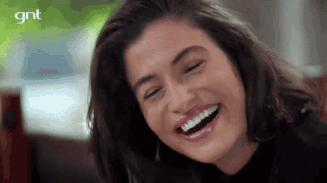 a close up of a woman laughing with a gnt logo behind her