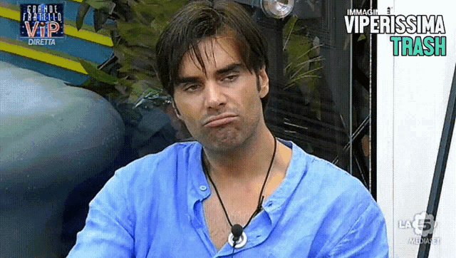 a man in a blue shirt is making a funny face in front of a sign that says viperissima trash