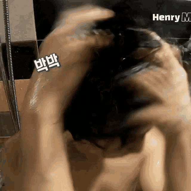 a person washing their hair in a bathroom with henry m. written on the wall behind them