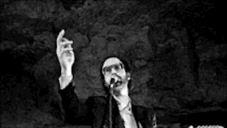 a man is playing a guitar and singing into a microphone while standing on a stage .