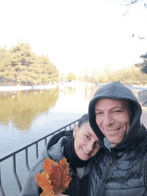 a man and a woman are posing for a picture with a lake in the background
