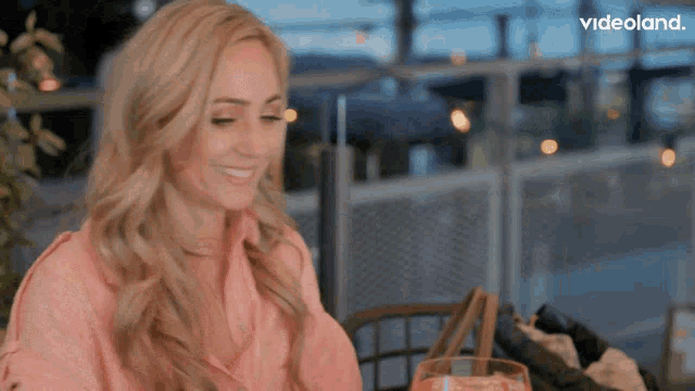a woman sits at a table with a glass of orange juice in front of a videoland advertisement