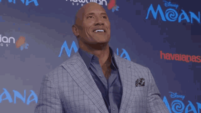 a man in a suit stands in front of a blue background with the word moana on it