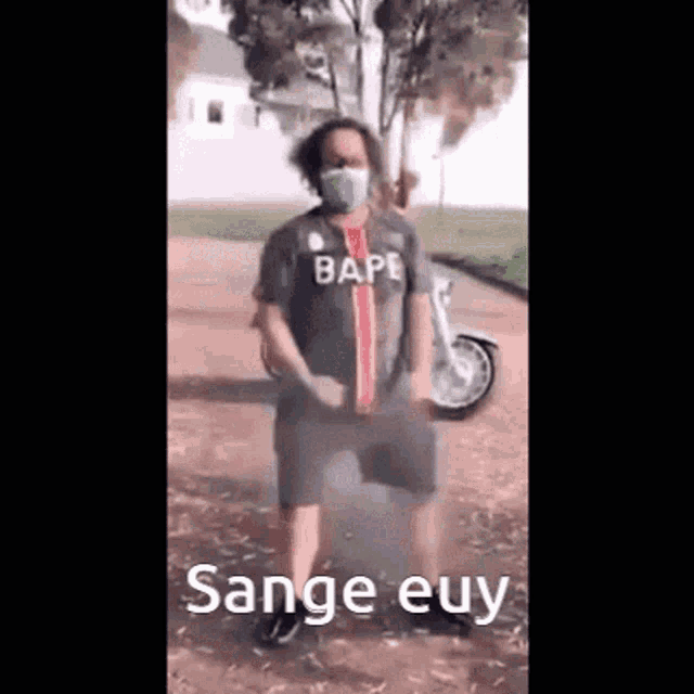 a man wearing a mask is dancing in front of a motorcycle .