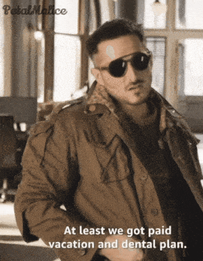 a man wearing sunglasses and a jacket with the words at least we got paid vacation and dental plan