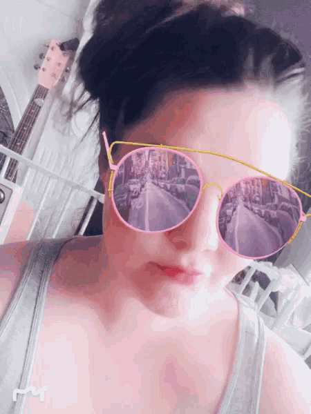 a woman wearing sunglasses with a reflection of a street