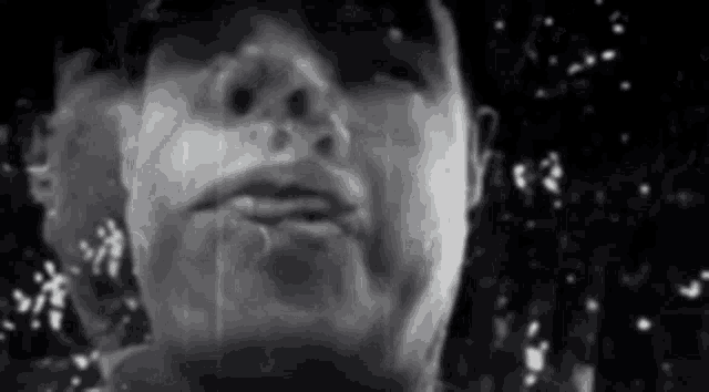 a black and white photo of a man 's face with rain drops on it .