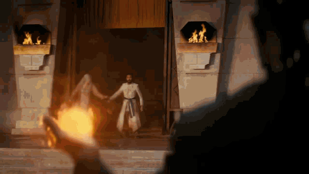 a man and a woman are holding hands in front of a building with flames coming out of it