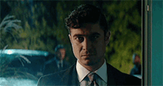 a man in a suit and tie is standing in front of a blue door .