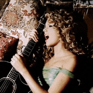 a woman singing into a microphone while holding an acoustic guitar