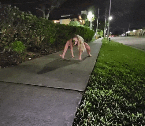 a woman is walking down a sidewalk at night .
