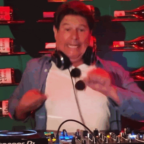 a man wearing headphones and sunglasses is standing in front of a pioneer dj mixer