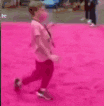 a little girl walking on a pink carpet with a lanyard around her neck