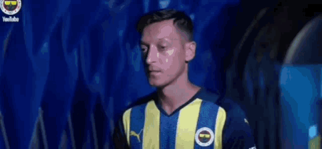 a man wearing a blue and yellow striped soccer jersey is standing in a tunnel .