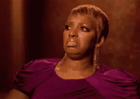a woman in a purple dress is making a funny face while sitting down .