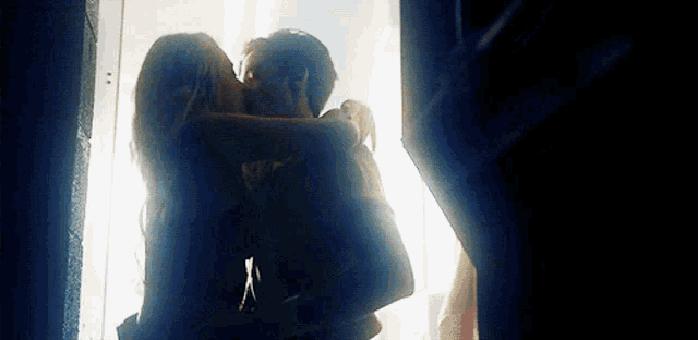a man and woman are kissing in a dark room .