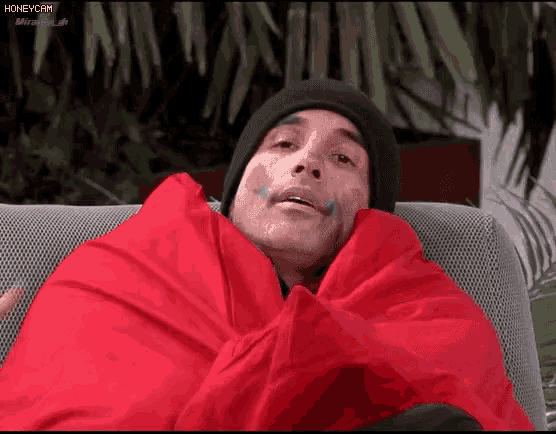 a man is wrapped in a red blanket while wearing a black beanie