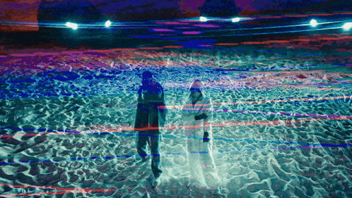 a man and a woman are walking on a beach at night
