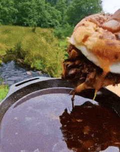 a hamburger is being dipped into a sauce in a skillet