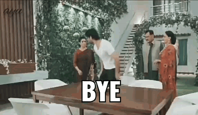 a man is standing in front of a wooden table with the word bye written on it .