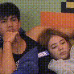 a man and a woman are laying on a couch . the man is wearing a shirt that says xrien .