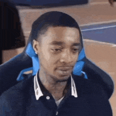 a man is sitting in a chair with a blue pillow on his back .