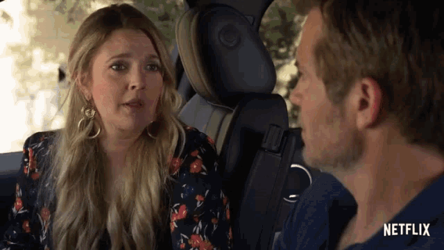 a man and a woman are sitting in a car with netflix written on the bottom of the screen