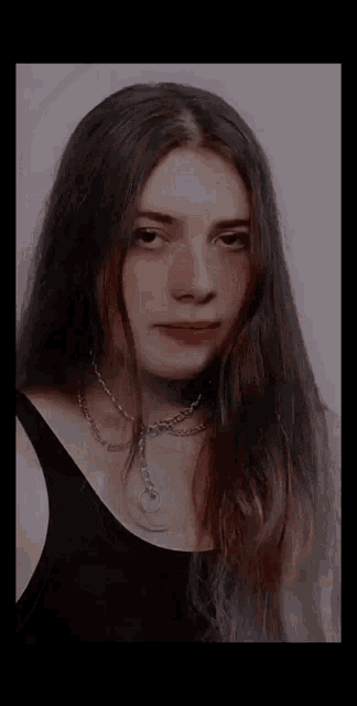 the girl is wearing a black tank top and a chain around her neck .
