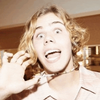 a young man with long blonde hair is making a funny face .