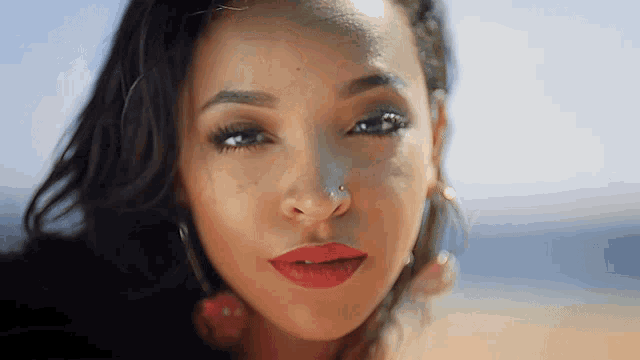a close up of a woman 's face with red lips and a nose ring