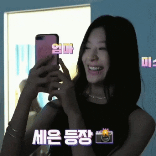 a woman is smiling while taking a picture of herself with her cell phone .