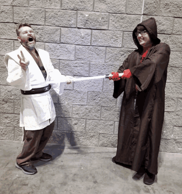 a man in a white robe is holding a light saber and a woman in a brown robe is holding a red light saber