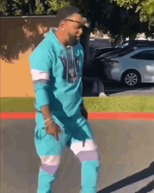 a man in a blue outfit is dancing on the sidewalk