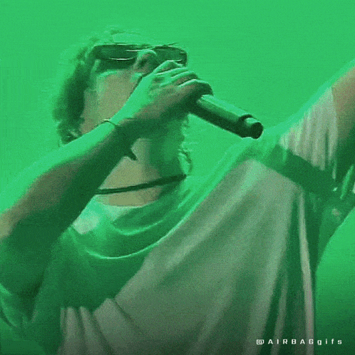 a man is singing into a microphone with a green background