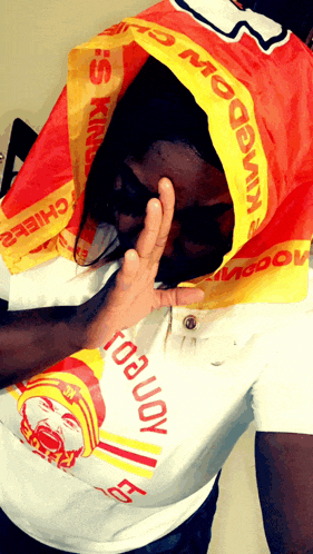 a man wearing a mcdonald 's shirt is covering his face