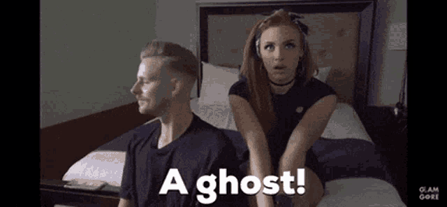 a man and a woman are sitting on a bed with the words a ghost written on the bottom .