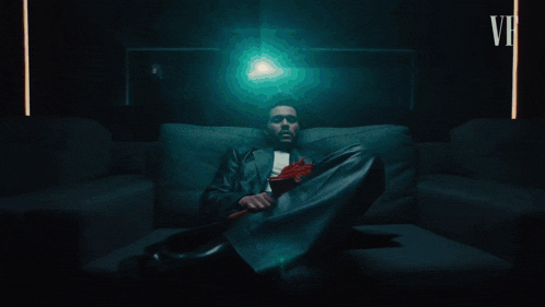 a couch in a dark room with a remote control and a red cup on the floor