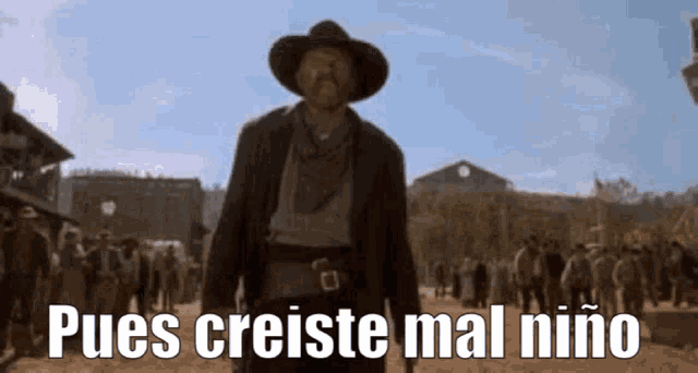 a man in a cowboy hat is standing in front of a crowd with the words pues creiste mal niño below him