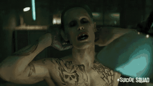 a close up of a person with a suicide squad advertisement behind them