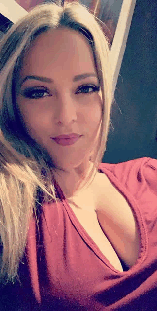 a woman in a red top is taking a selfie with her eyes closed