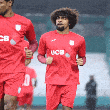 a man in a red ucb jersey is running on the field