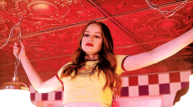 a woman in a yellow crop top is hanging from a ceiling