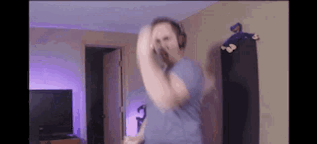 a man wearing headphones is dancing in a living room in front of a tv .