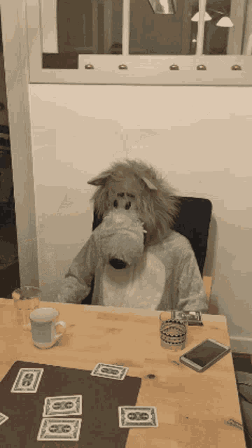 a person wearing a wolf costume sits at a table with playing cards