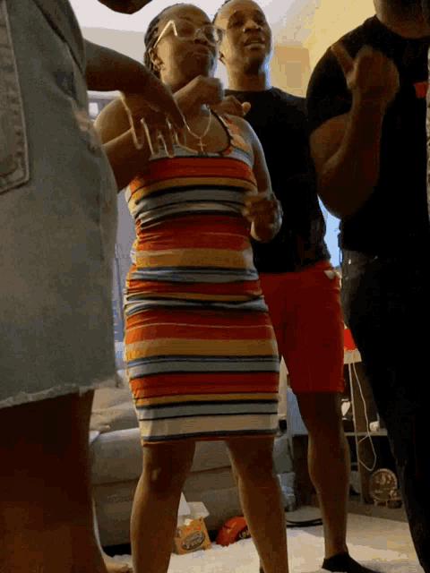 a woman in a striped dress stands in a room with other people