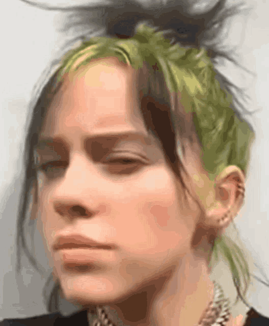a close up of billie eilish 's face with her eyes closed and her hair in a bun